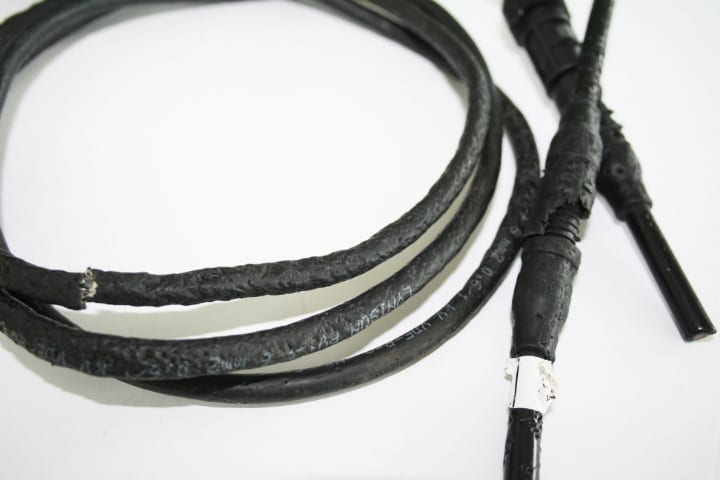 Coiled black DC cable with one end showing damaged, exposed conductor