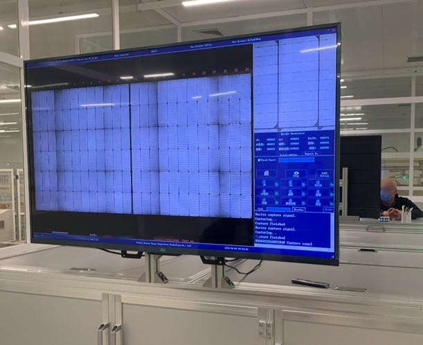 Screenshot of a large monitor displaying EL test images of multiple panels on the factory floor