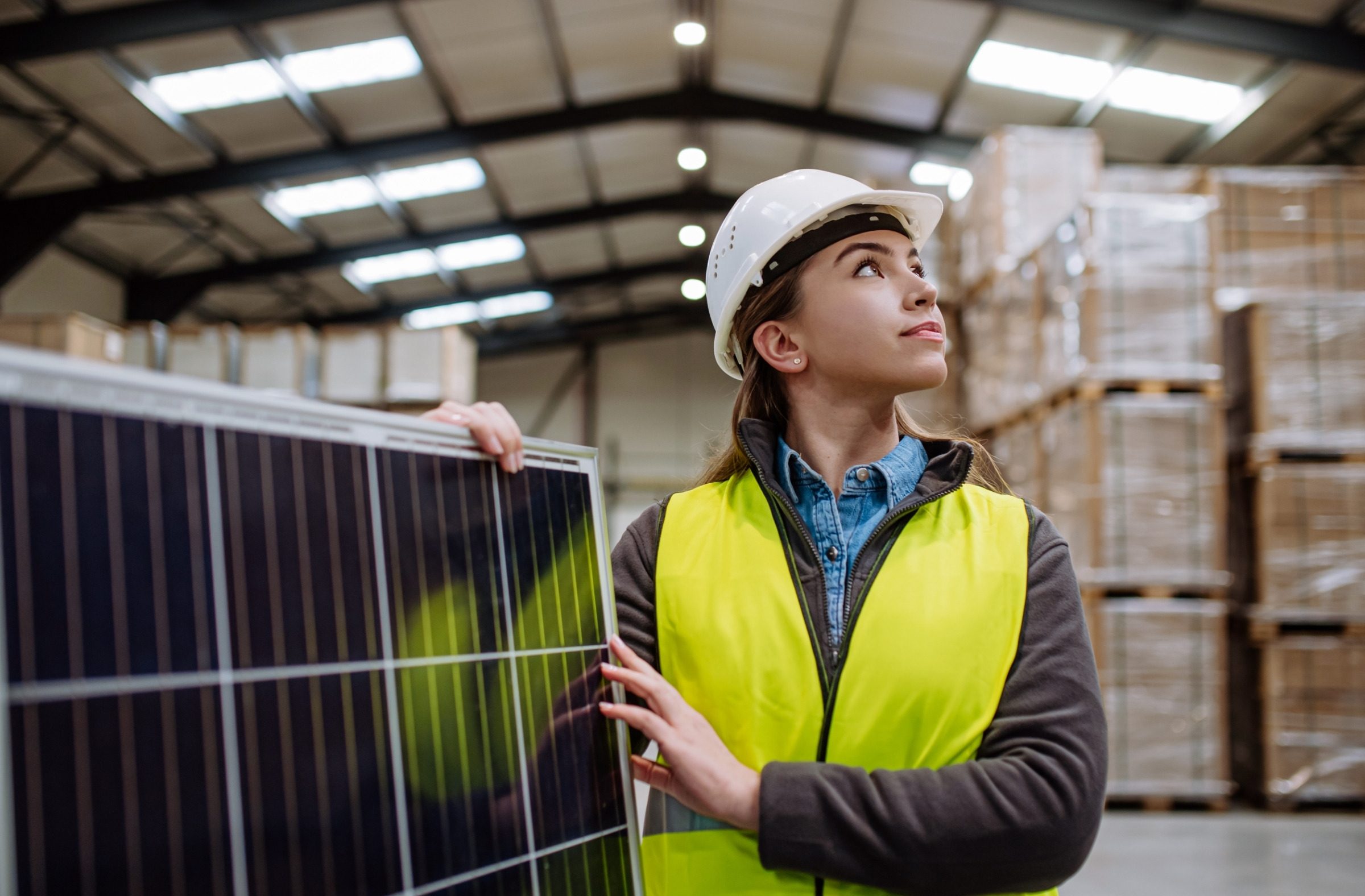 An engineer holding a solar module in a warehouse