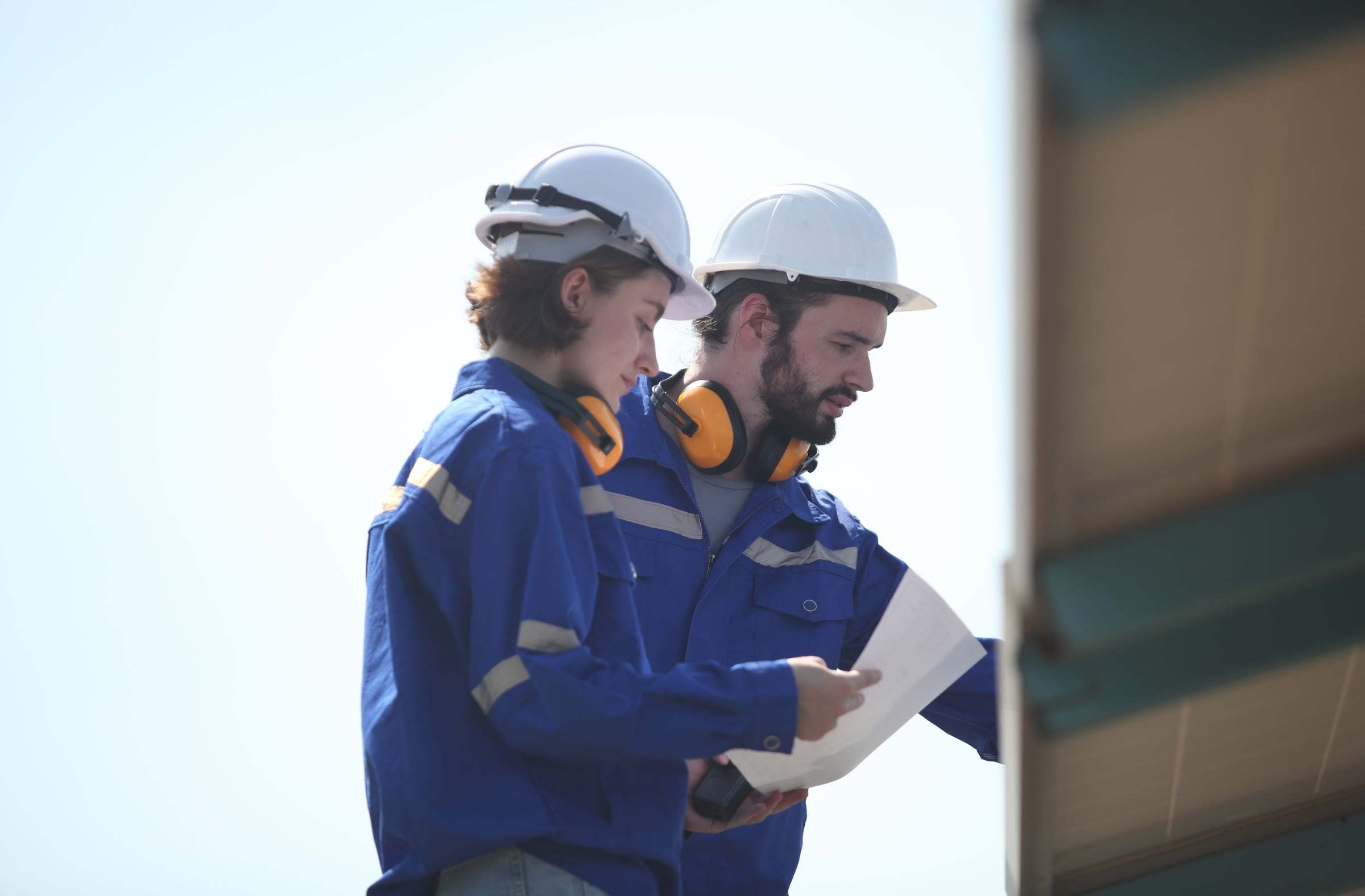 Two engineers in hard hats reviewing documents at a solar plant